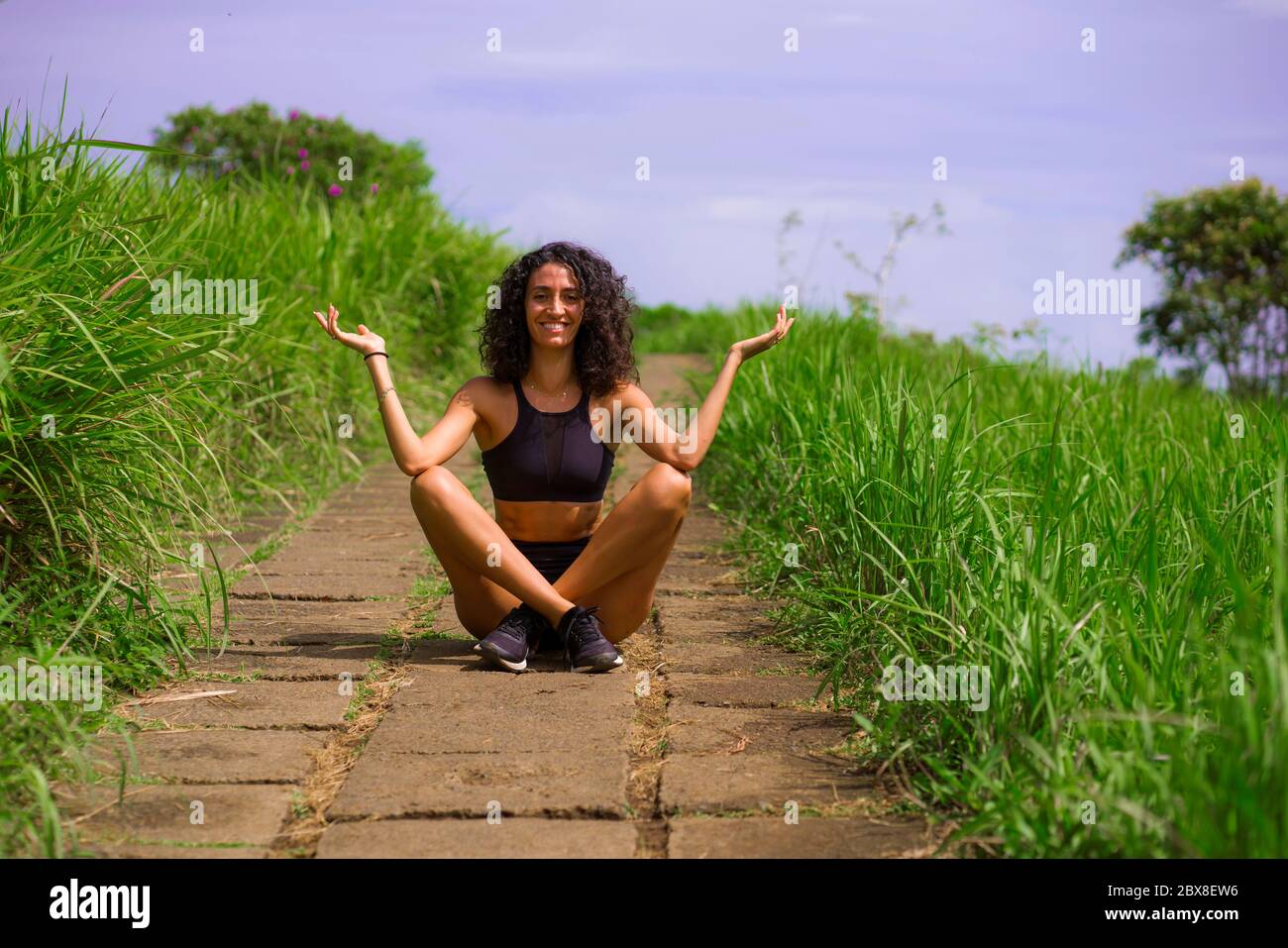 fresco e naturale stile di vita ritratto di giovane attraente e felice hipster donna con capelli ricci in abiti fitness godendo la natura all'aperto sorridente c Foto Stock