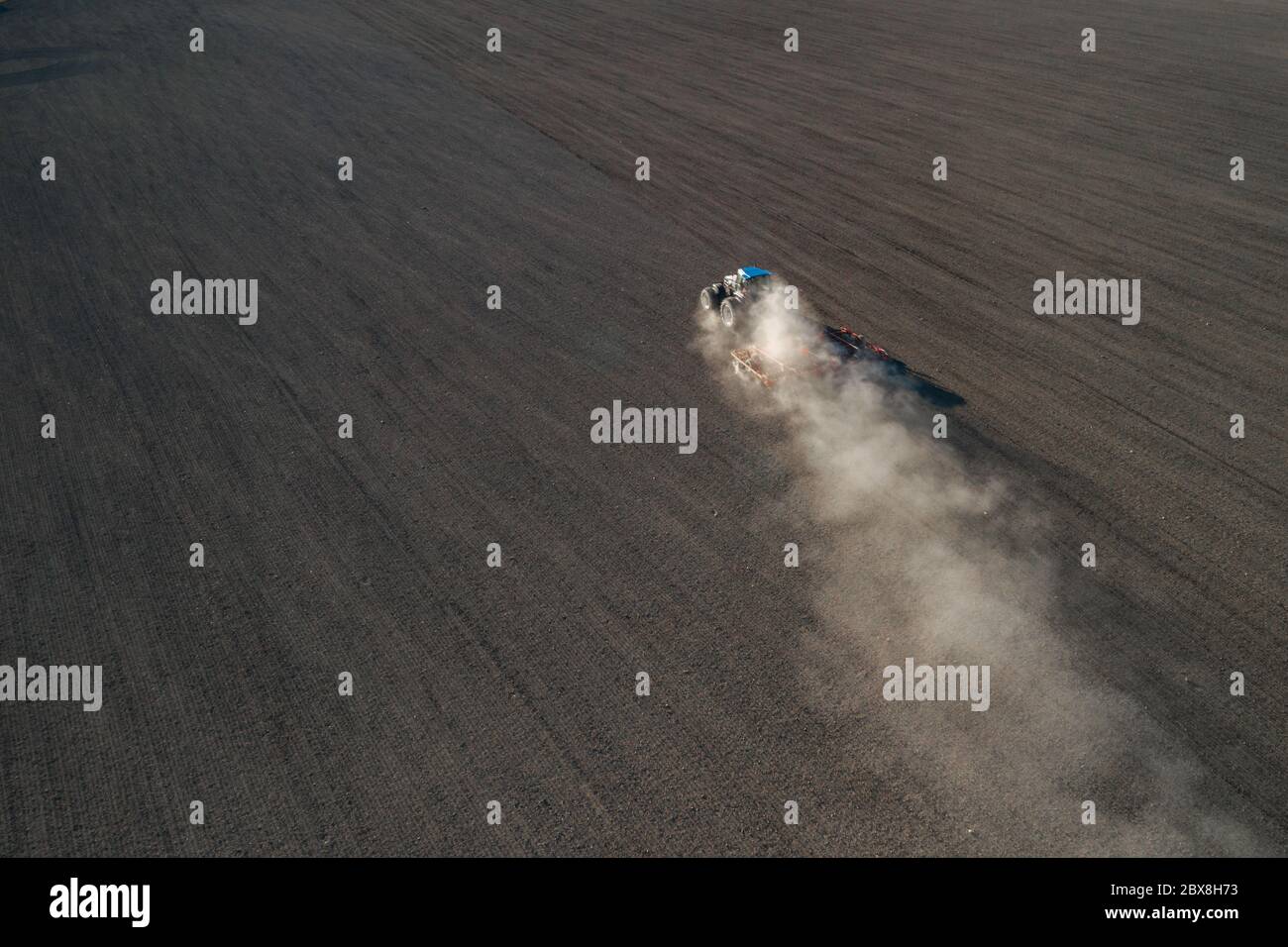 Vista aerea di un trattore che semina grano su un campo agricolo Foto Stock