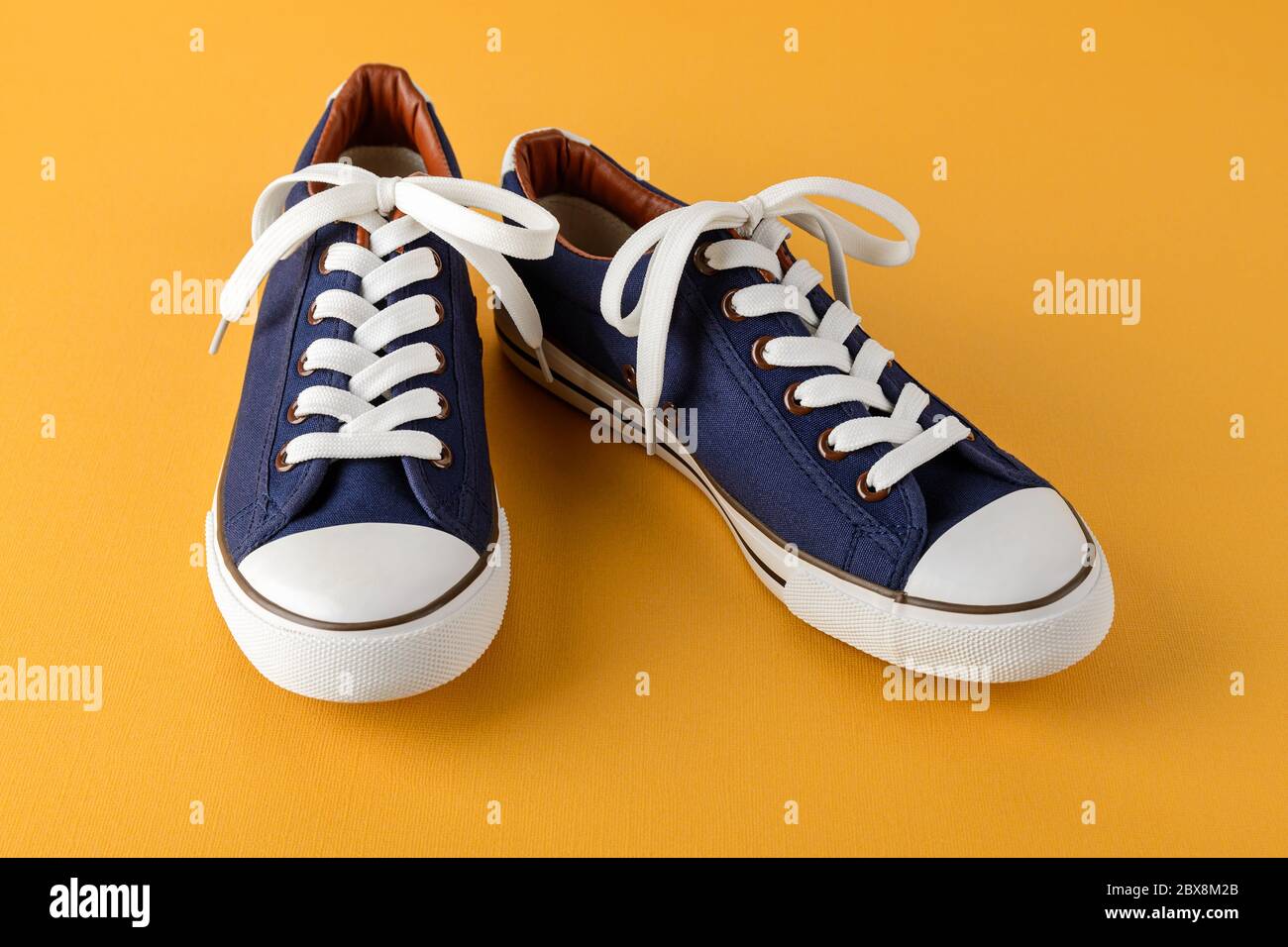 Paio di sneaker o scarpe da ginnastica blu con lacci bianchi su sfondo  giallo brillante e testurizzato. Scarpe comode per il fitness e lo sport.  Vista frontale Foto stock - Alamy