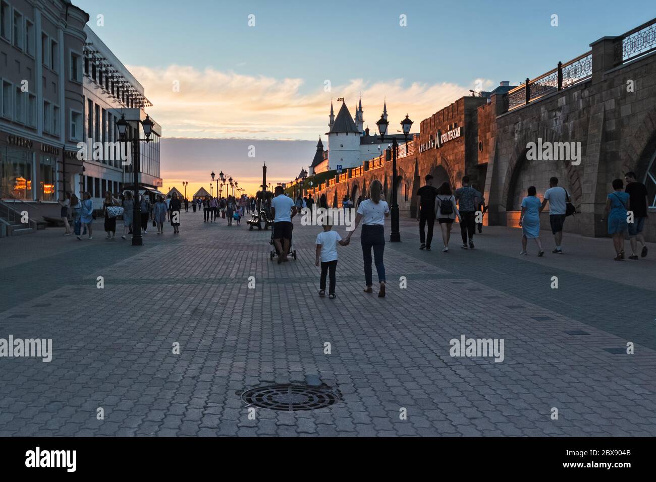 Le mura del Cremlino Kazan all'esterno, illuminate dal tramonto, le persone camminano lungo la strada. Russia, Kazan 24 giugno 2019 Foto Stock