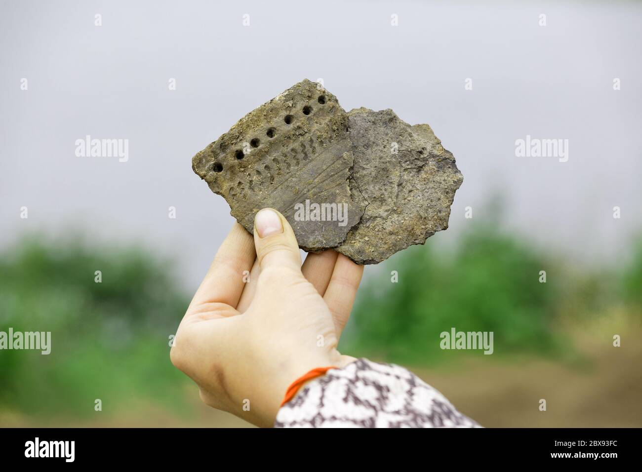 Due pezzi di antico vaso di argilla in mano di un archeologo. Ricreazione nella forma originale Foto Stock