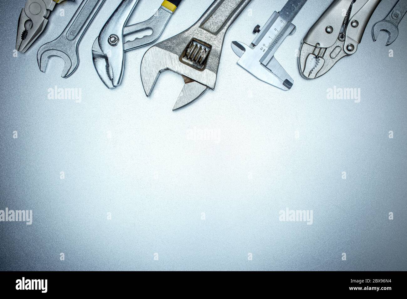 vista dall'alto del set di utensili manuali su sfondo grigio, incluse chiavi, chiavi, pinze e calibro a corsoio Foto Stock