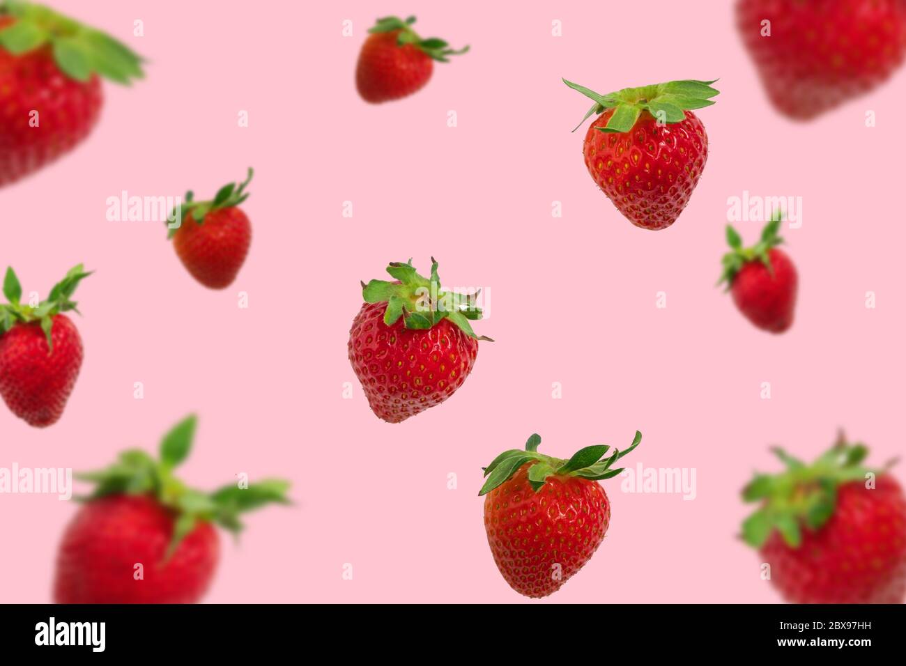 Coloratissimo motivo di fragole che cadono su sfondo rosa pastello, sfondo fragola Foto Stock