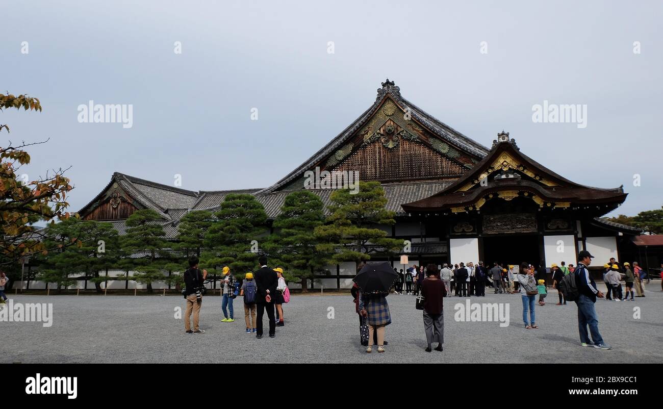 Unisciti ai tanti studenti ammirando l'intricato lavoro in legno della porta d'ingresso al castello di Nijo. Foto Stock