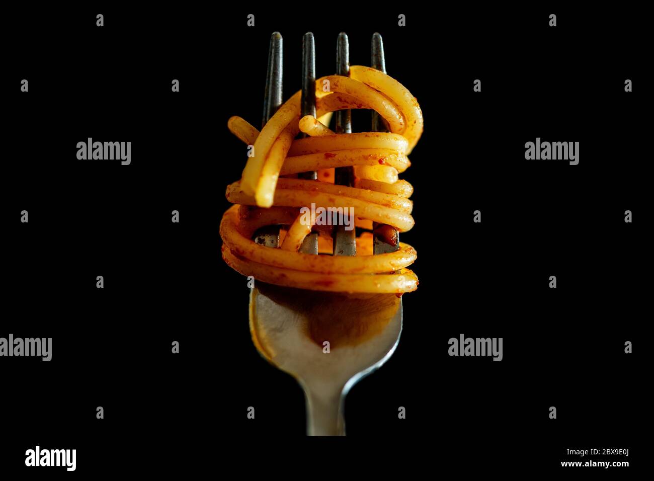 Primo piano di Spaghetti italiani su una forchetta con salsa di pomodoro su fondo nero. Cucina tipica italiana, stereotipo per identificare la cultura italiana. Foto di alta qualità Foto Stock
