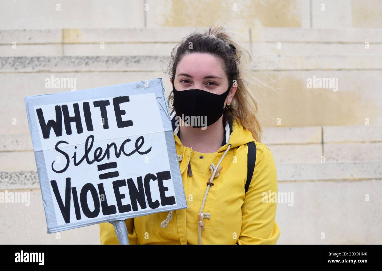 Una giovane donna caucasica protesta in un raduno britannico contro il razzismo nel Regno Unito con un segno che recita "il silenzio bianco equivale alla violenza" Foto Stock