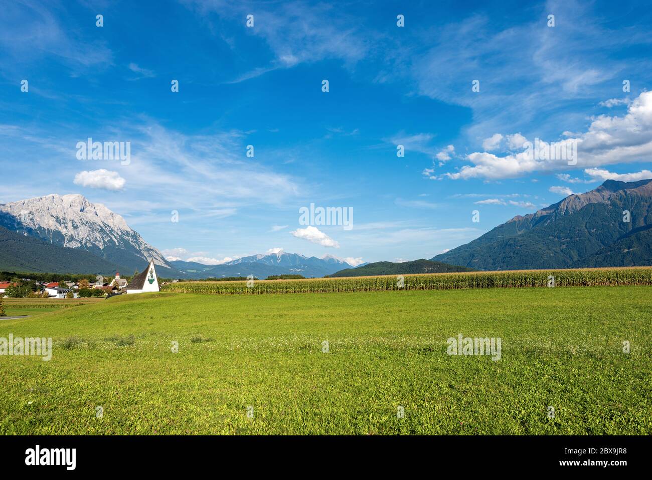 Prato, campo di mais e Alpi austriache nel piccolo villaggio di Obermieming, stato del Tirolo, Austria con la cima di Hohe Munde (2662 m), Mieming Range Foto Stock