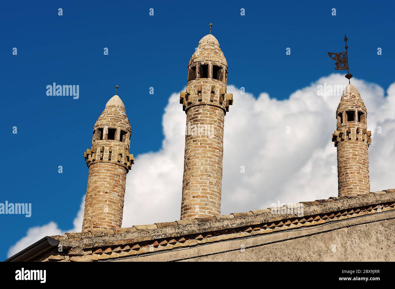Primo piano di tre antichi camini e tetto su un cielo blu con nuvole. Provincia di Verona, Veneto, Italia, Europa Foto Stock