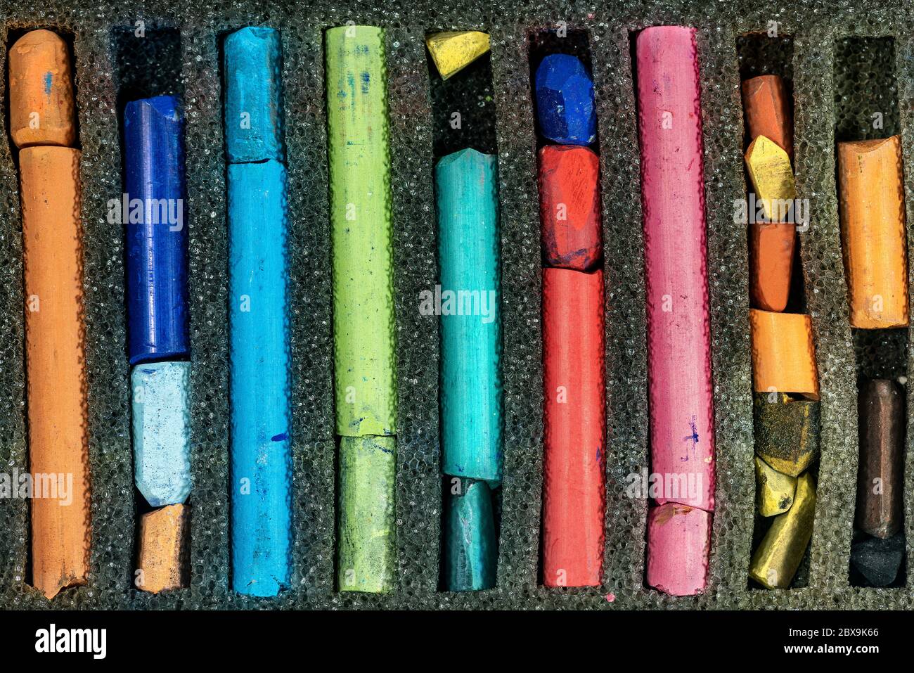 Primo piano estremo di bastoncini pastello usati in una scatola Foto Stock