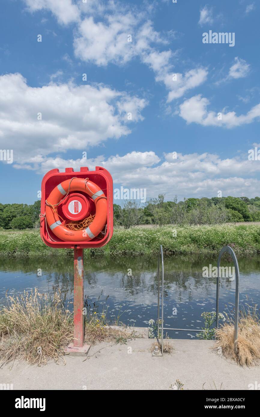Anello di salvataggio rosso-arancio luminoso illuminato al sole in una casa sul fiume Fowey a Lostwithiel. Per la sicurezza, il pericolo, la permanenza a galla, possibilmente la valutazione dei rischi Foto Stock