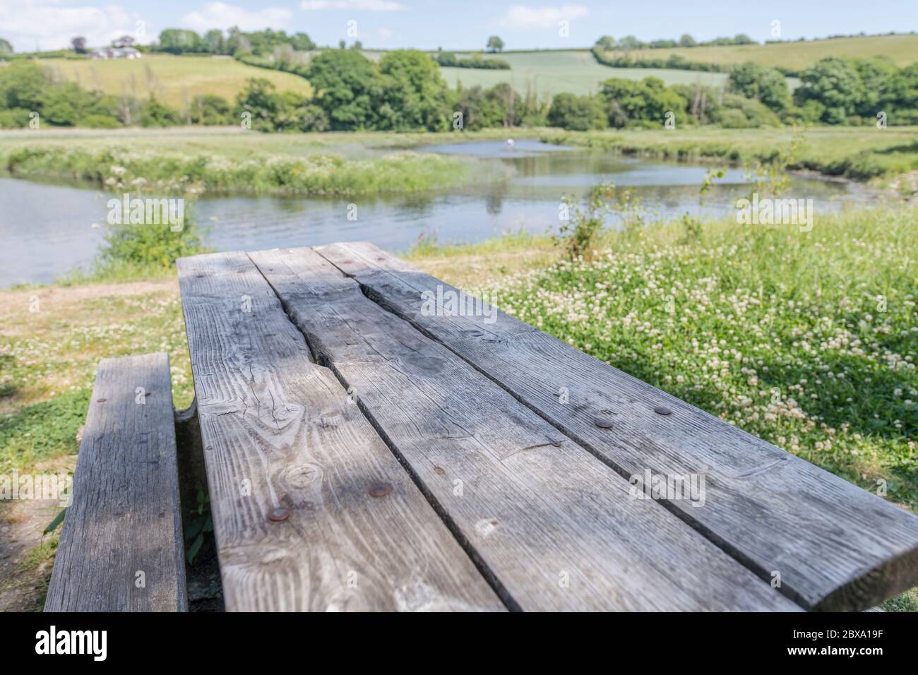 Tavolo da picnic pubblico vuoto al sole accanto alle acque del fiume Fowey a Lostwithiel, metafora spazi pubblici vuoti durante il blocco Covid-10. Foto Stock