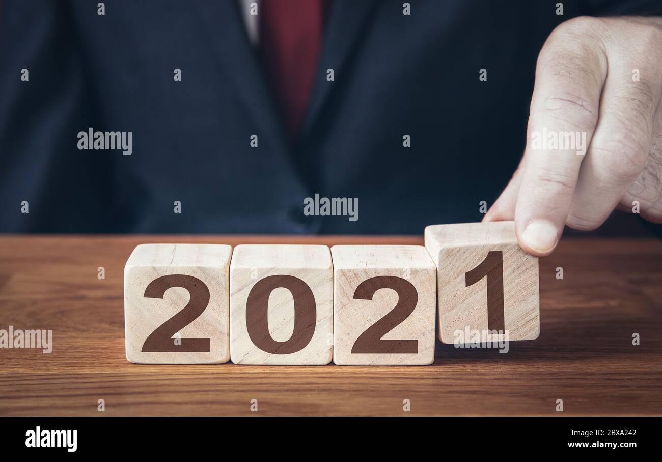 Un primo piano di un uomo d'affari che guarda avanti al futuro con fiducia e cambia la data di un calendario a 2021 Foto Stock