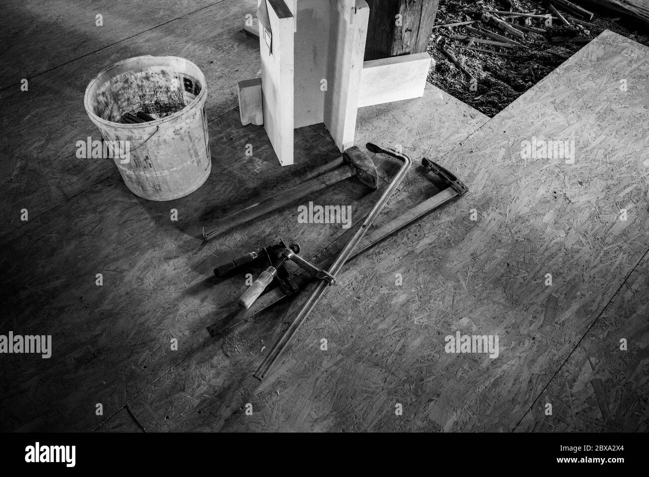 in un cantiere due morsetti in acciaio, un martello grande e un cucchiaio sono affiancati Foto Stock