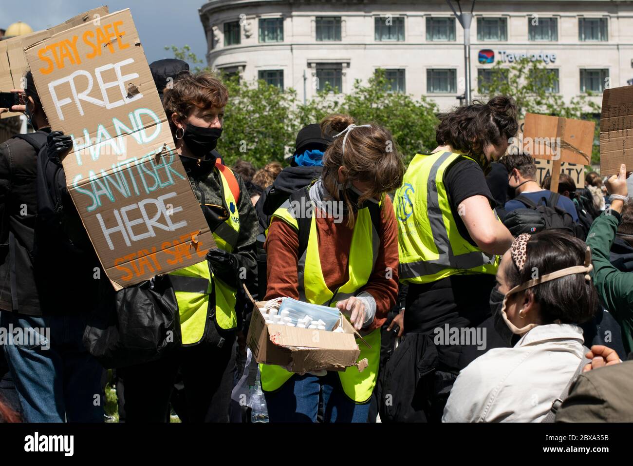 Black Lives Matter protesta Manchester UK. L'igienizzatore per le mani viene consegnato ai manifestanti da donne in giacche ad alta visibilità e maschere facciali. Foto Stock