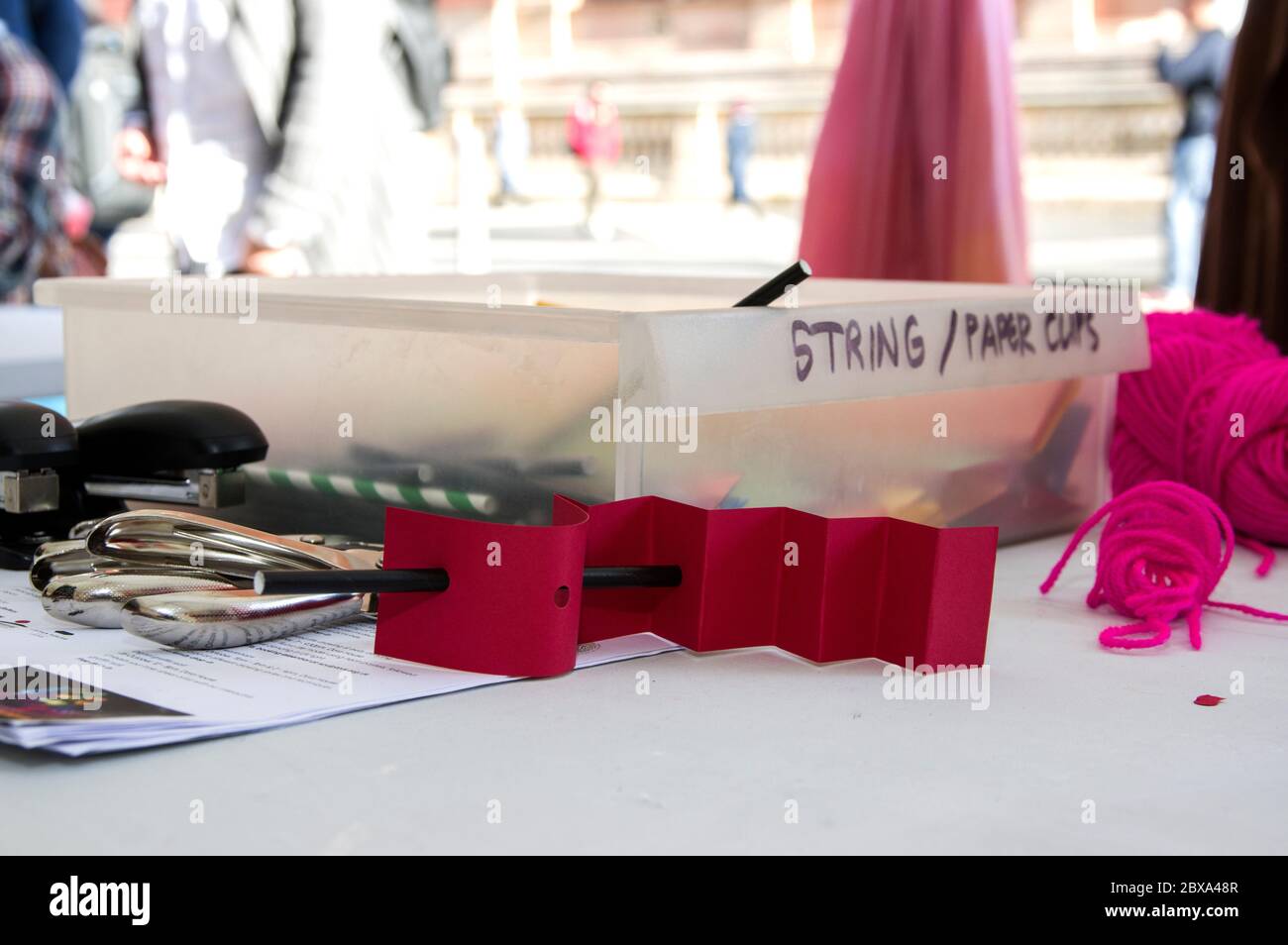 scatola di plastica con etichetta stringa e tagli di carta in uno stallino esterno con perforatori e carta piegatrice in primo piano Foto Stock