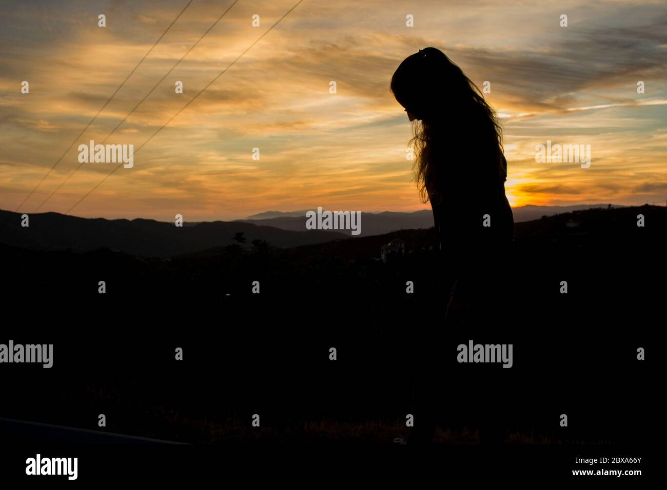 Silhouette di una ragazza con un tramonto sullo sfondo. Foto Stock