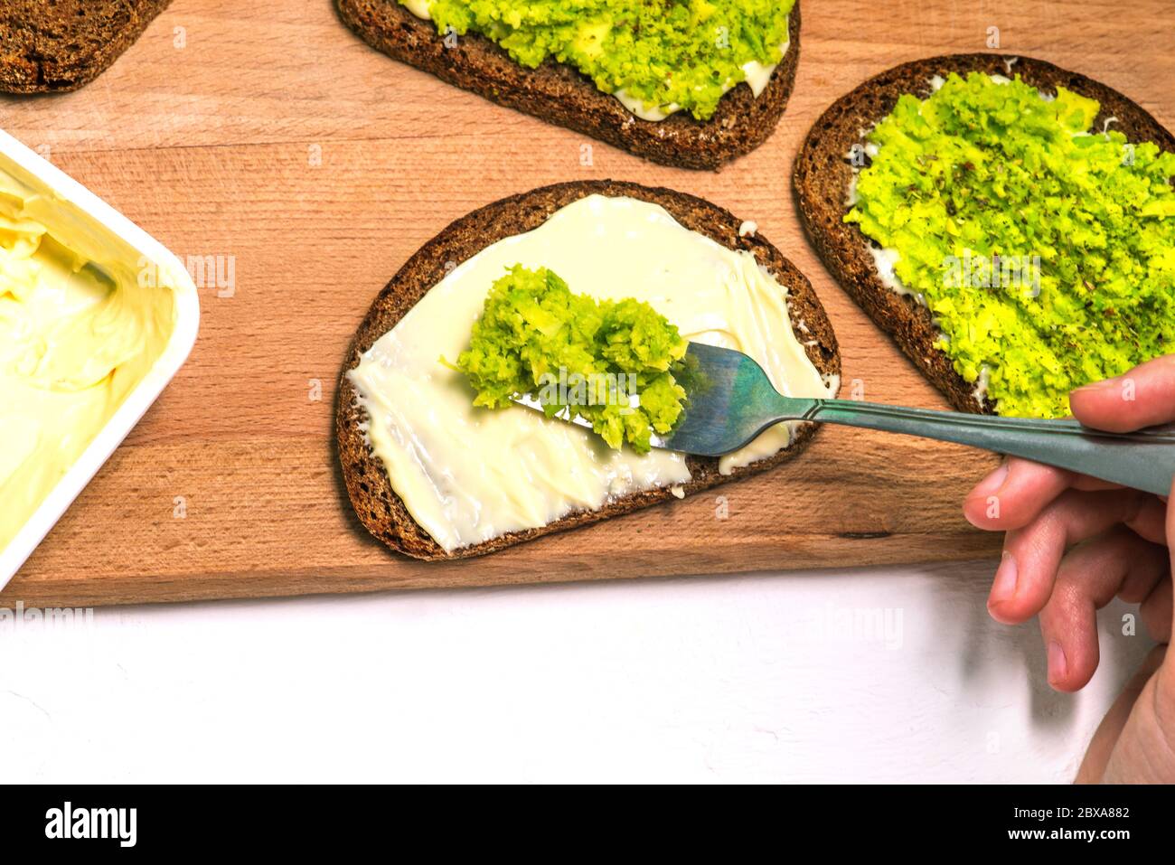 Purea di avocado su una forchetta. Preparare toast all'avocado. Ricetta vegetariana. Una vista dall'alto di un layout piatto. Foto Stock