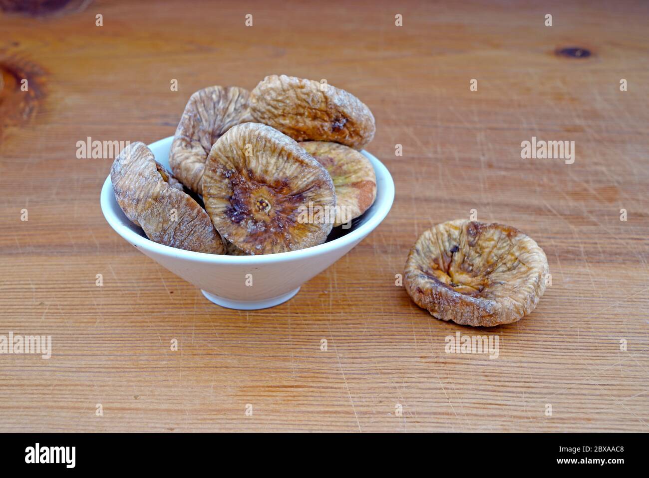 Piatto di fichi secchi organici e fichi secchi versato su sfondo di legno Foto Stock