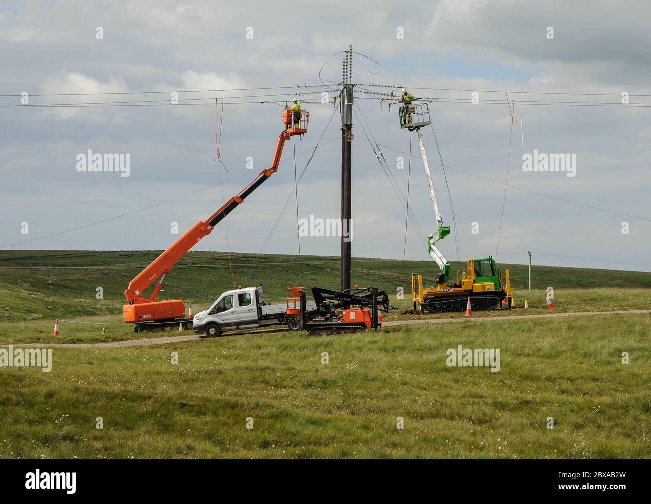 Linesmen su piattaforme mobili di lavoro sopraelevate che costruiscono un nuovo collegamento elettrico a windfarm.in Dumfries e Galloway Foto Stock