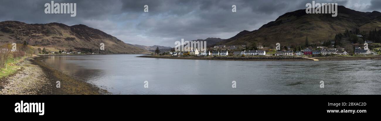 Vista panoramica del villaggio di Dornie attraverso Loch Long con cielo nuvoloso e luce solare irregolare sul villaggio e la costa Foto Stock