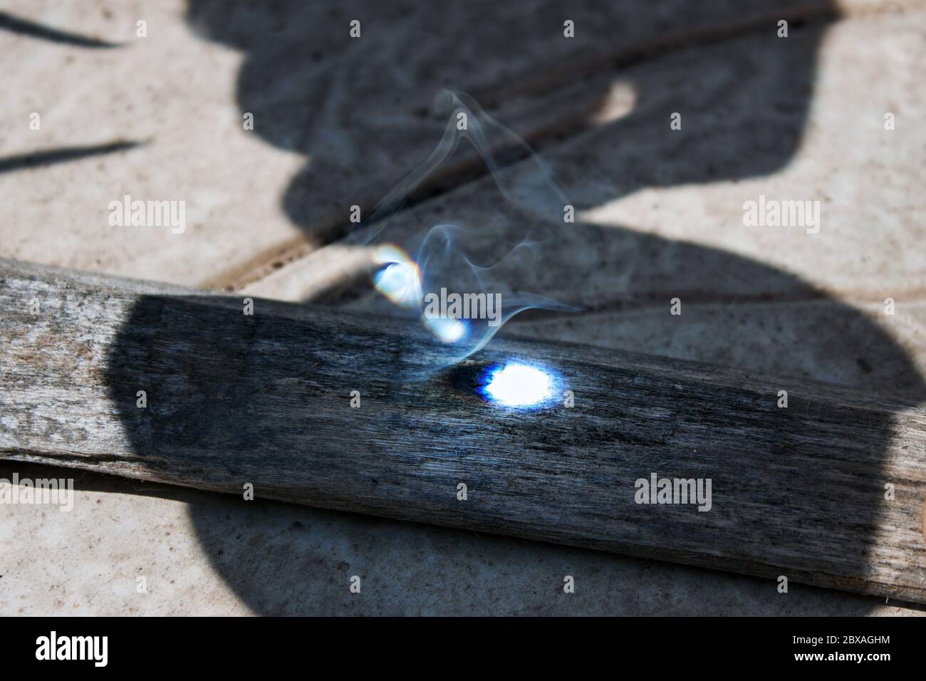 avviare un fuoco con una lente di ingrandimento su un legno Foto Stock