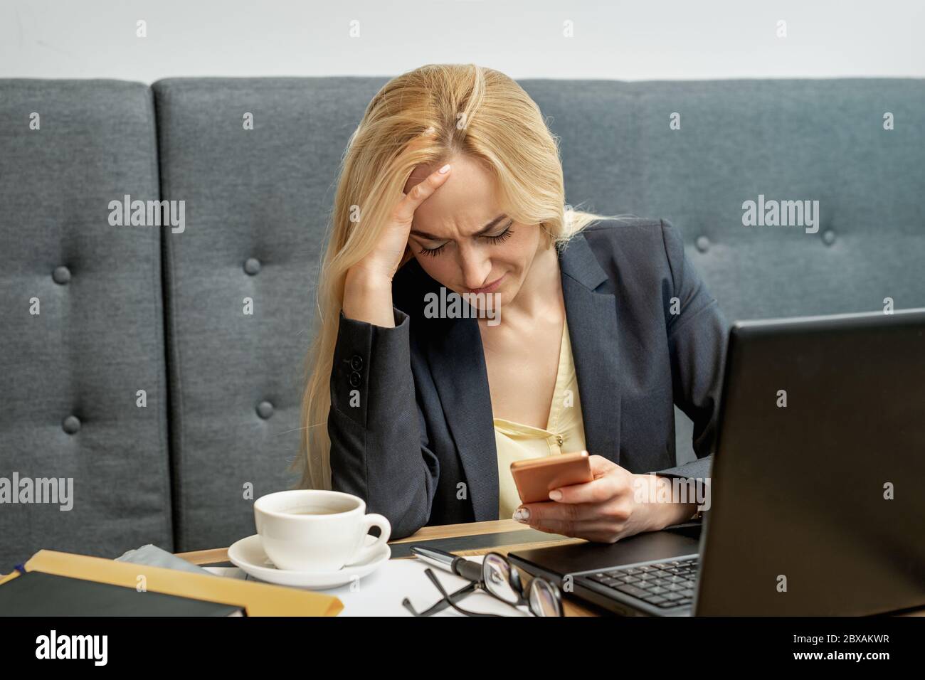 Donna che guarda sorpreso mentre usa lo smartphone sul posto di lavoro a casa. Foto Stock