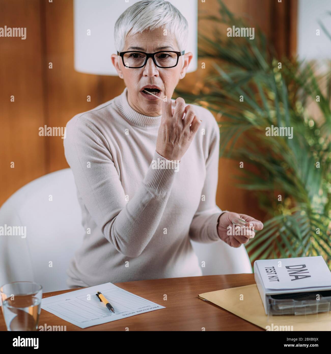 Donna anziana che fa un test del DNA a casa Foto Stock