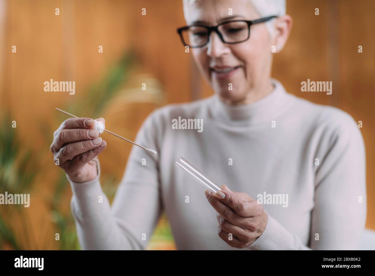 Donna anziana che fa un test del DNA a casa Foto Stock