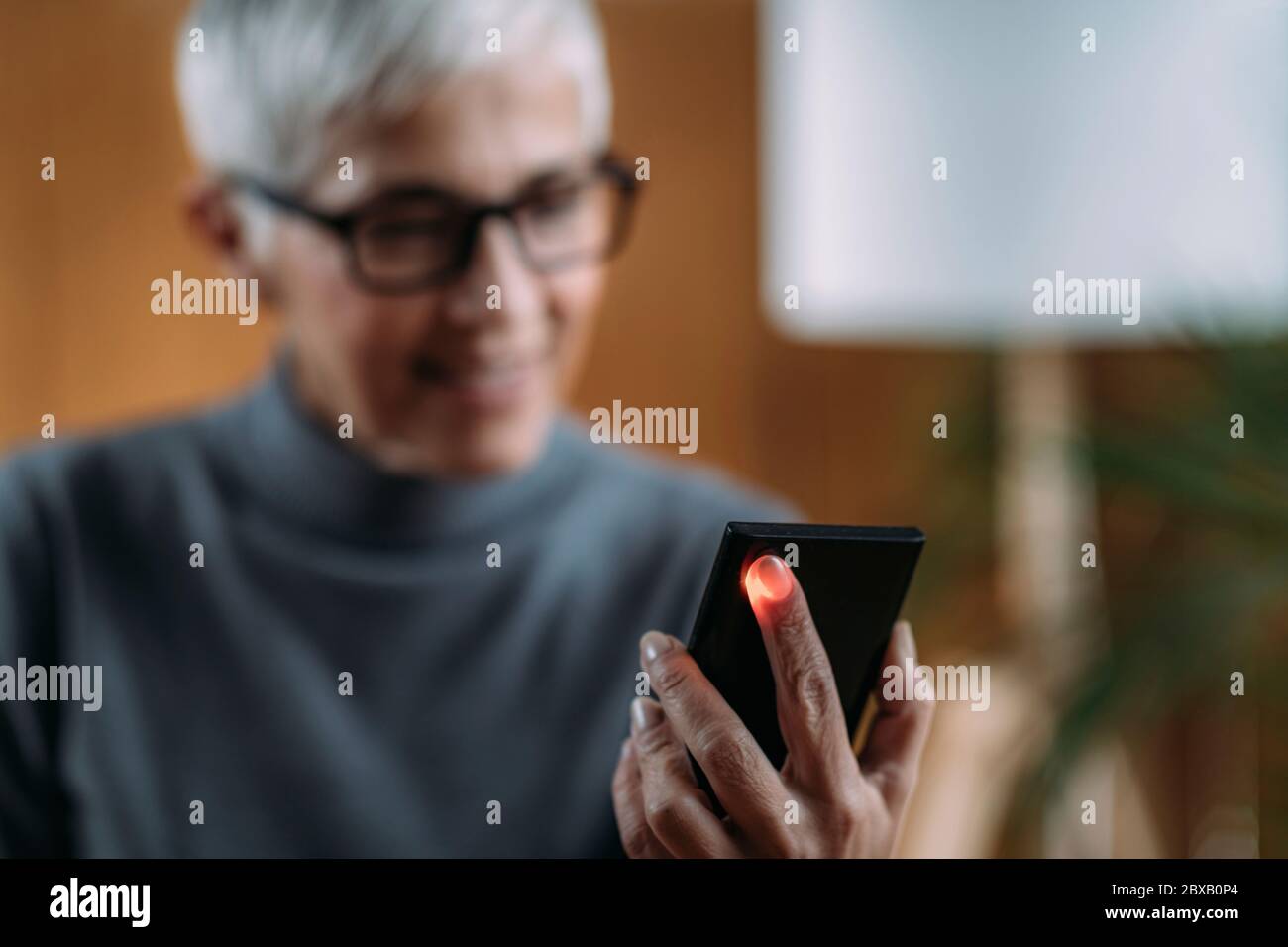 Donna anziana che misura la frequenza cardiaca con smartphone Foto Stock