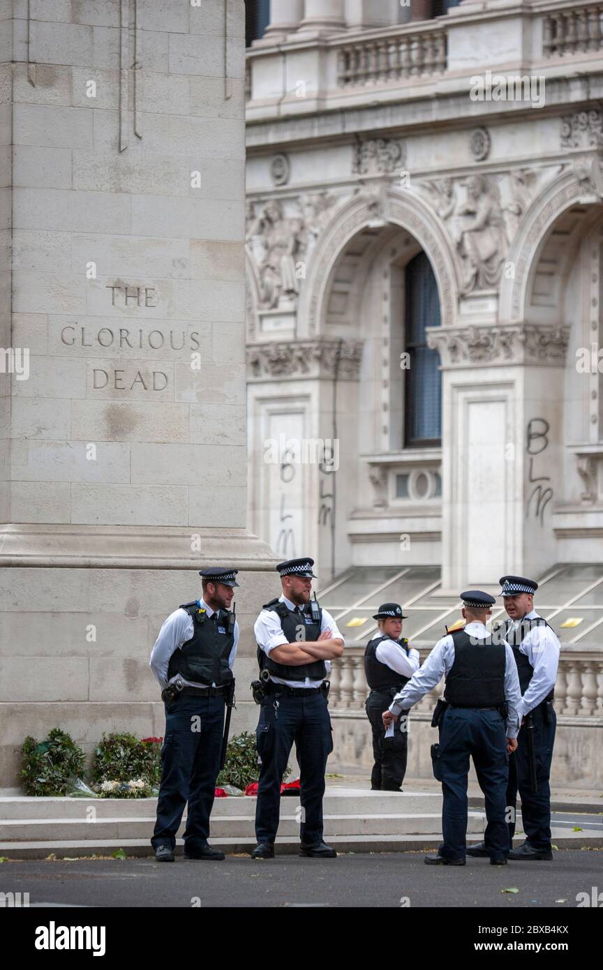 Gli ufficiali di polizia britannici si trovano di fronte al monumento "i gloriosi morti" di fronte agli edifici di Whitehall con graffiti spruzzati di BLM. Londra UK Foto Stock