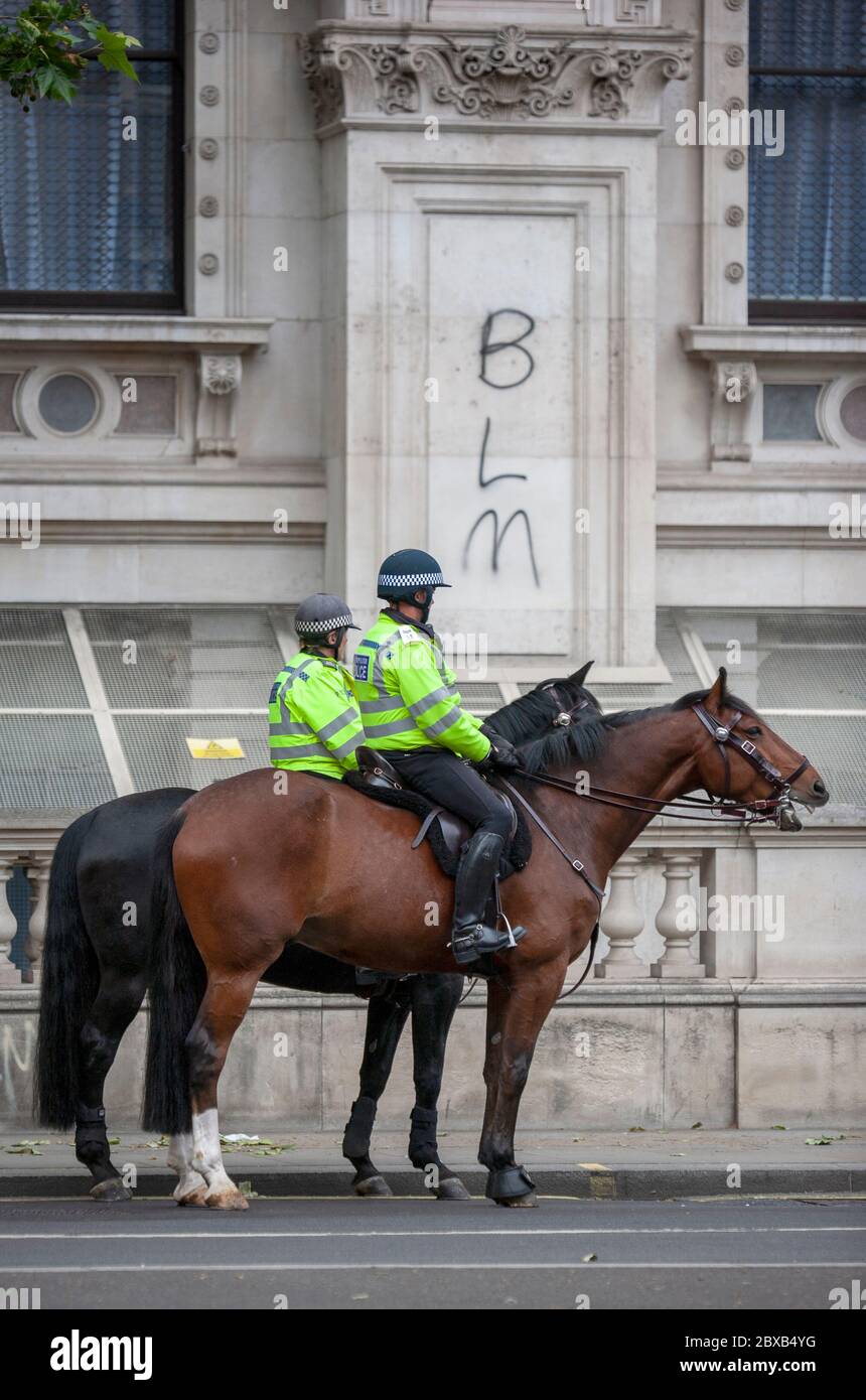 Due poliziotti a cavallo di fronte ai graffiti BLM. Whitehall, Londra, Inghilterra, Regno Unito Foto Stock