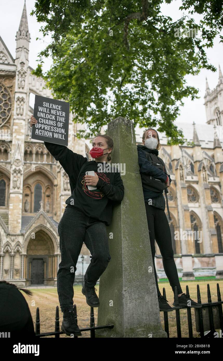 Due manifestanti sulle ringhiere di Westminster Abbey hanno un cartello che chiede di agire contro il razzismo durante la protesta nel centro di Londra, Regno Unito. Foto Stock