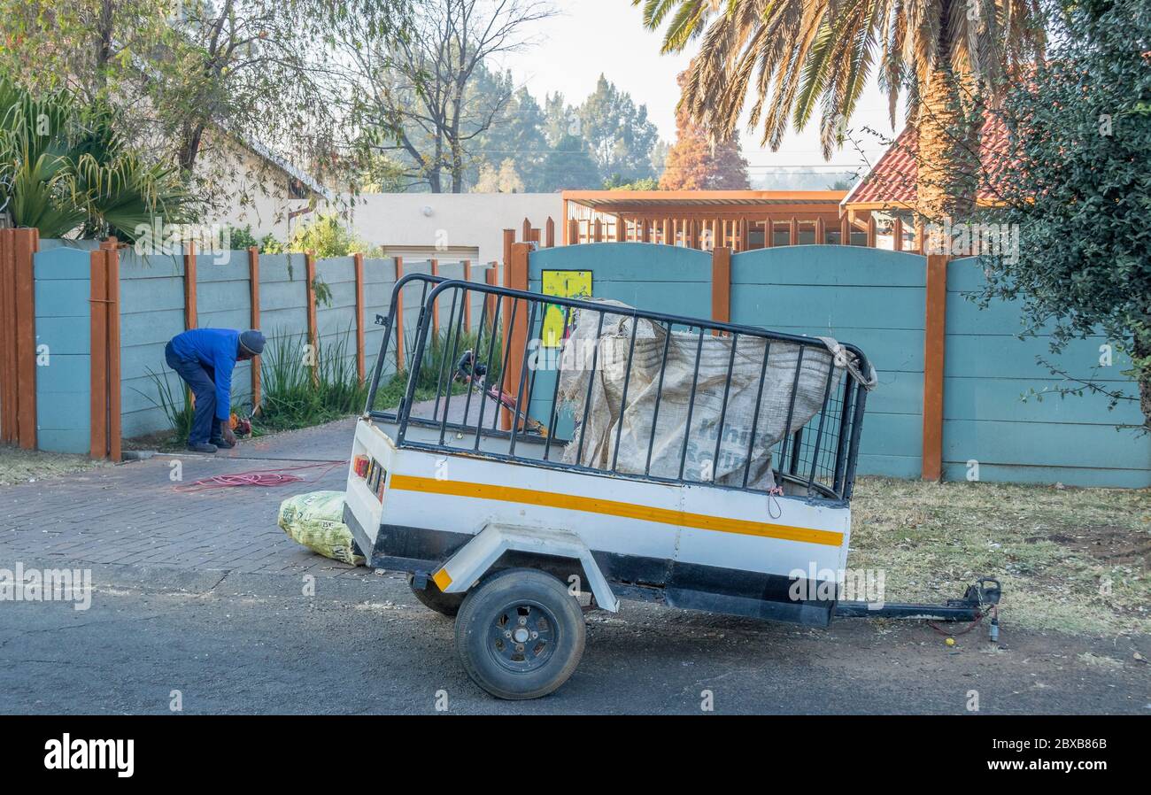 Alberton, Sudafrica - operatore di servizi di giardinaggio non identificato che si affida al suo commercio in un'immagine residenziale di sobborgo in formato orizzontale Foto Stock