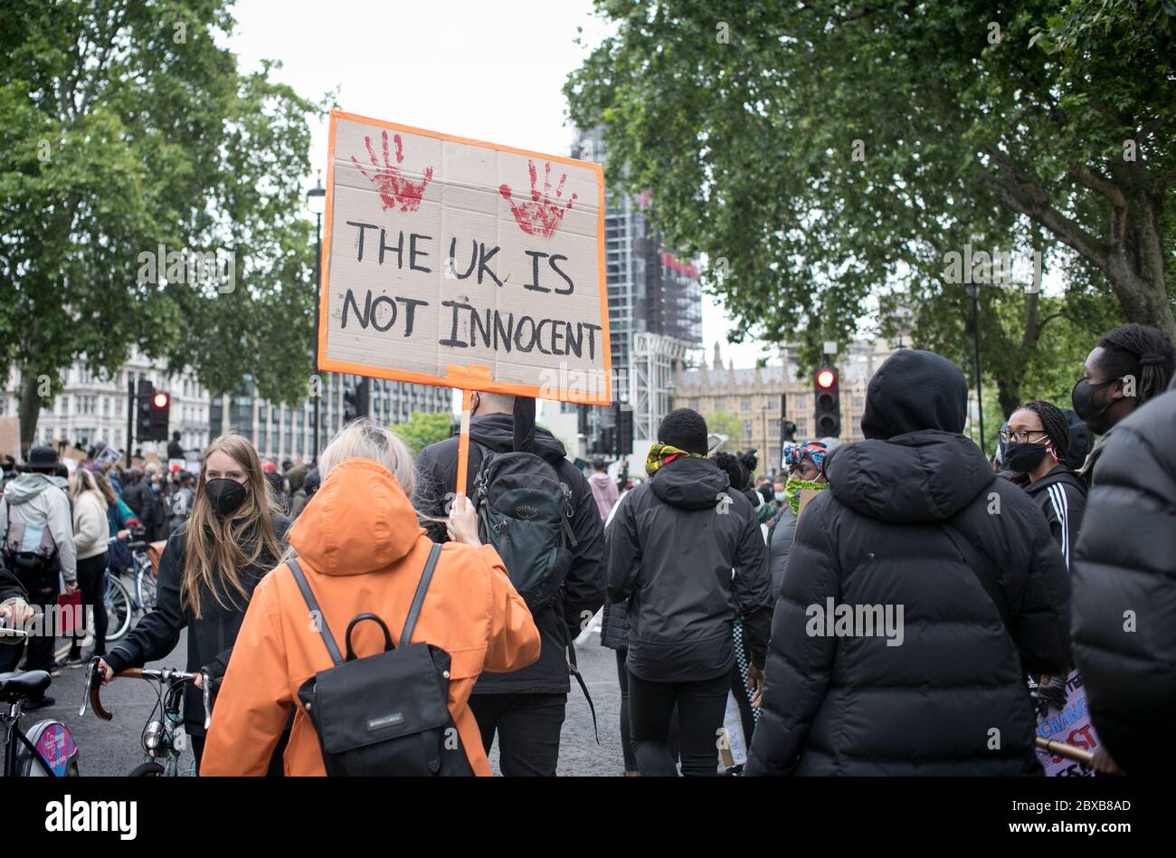Un manifestante tiene un cartello contro il razzismo sistemico nel Regno Unito cammina verso le Camere del Parlamento durante il rally tenutosi nel centro di Londra, Regno Unito. Foto Stock