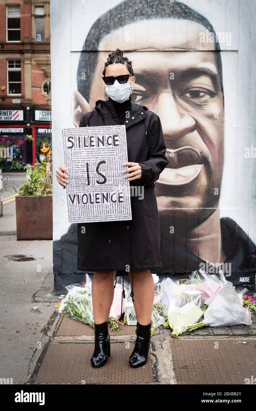 Un protettrice che tiene un cartello si trova di fronte ad un murale dipinto dall'artista di strada AKSE P19 durante la manifestazione. Diverse proteste sono state scatenate dalla recente uccisione di George Floyd, un uomo nero morto in custodia di polizia a Minneapolis, U.S.A. Foto Stock