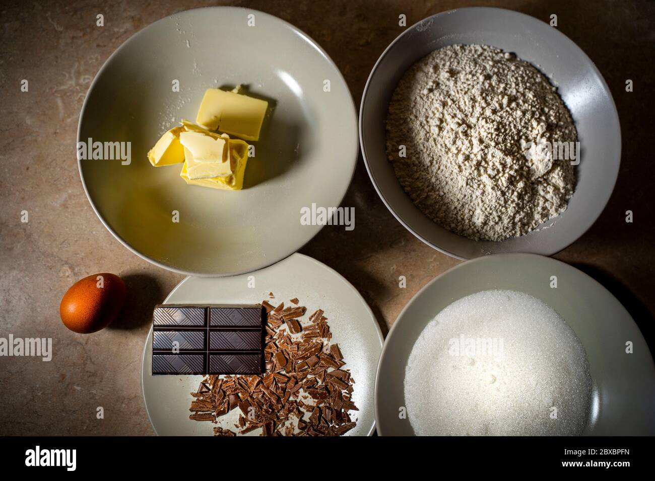 Ingredienti per la ricetta dolce. Uova, burro, farina, cioccolato, zucchero. Vista dall'alto. Foto Stock