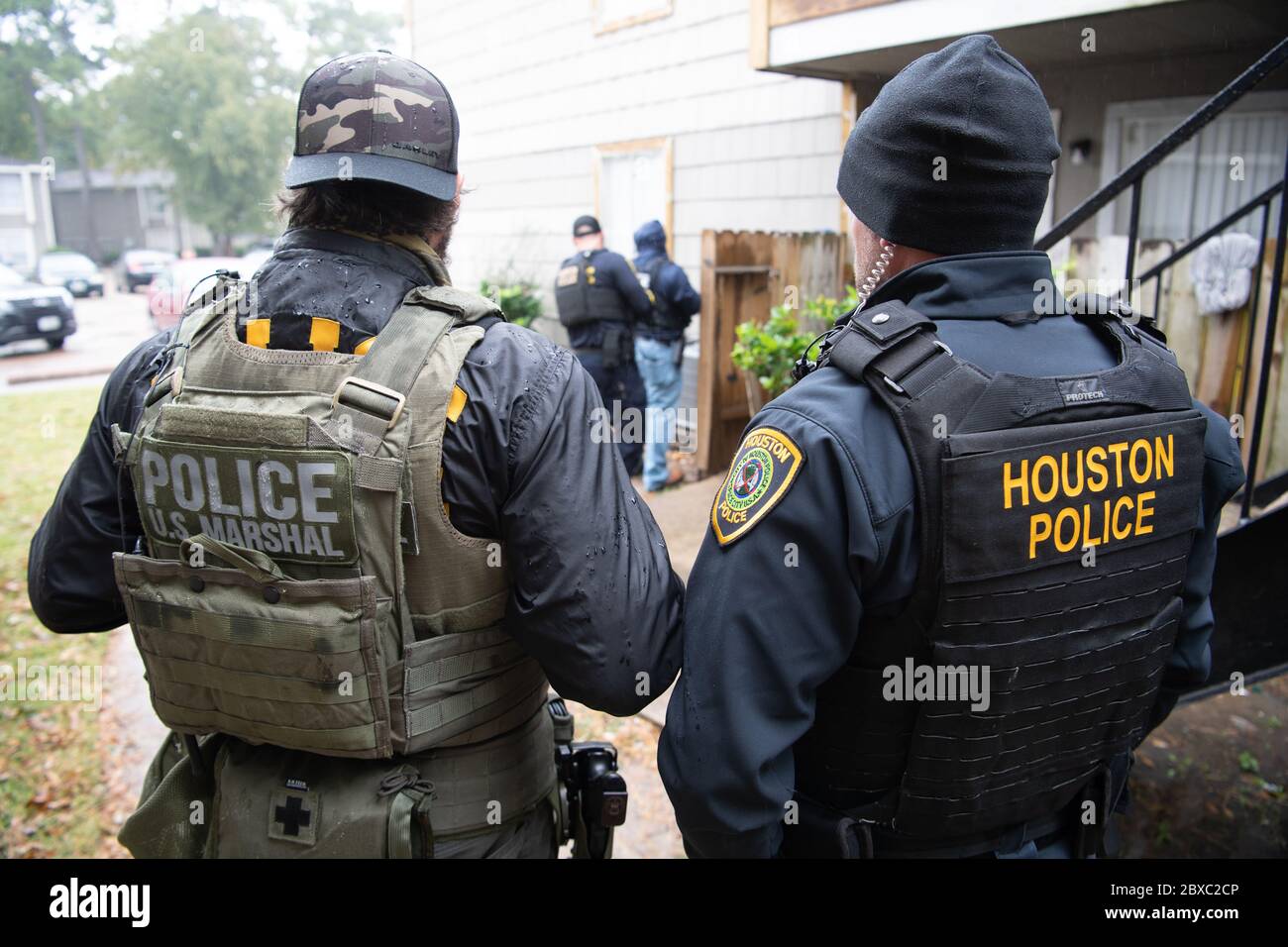 I marescialli degli Stati Uniti e la polizia di Houston guardano sopra come un membro della squadra cerca un fuggitivo durante 90-day, operazione multi-stato Triple Beam 14 novembre 2019 a Houston, Texas. L'operazione ha provocato più di 6,000 arresti in comunità colpite dalla violenza. Foto Stock