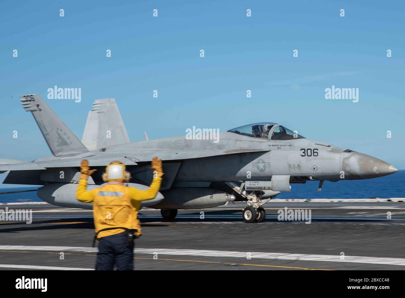 La giacca gialla della marina statunitense segnala un aereo da combattimento F/A-18E Super Hornet, attaccato a Eagles of Strike Fighter Squadron 115, dopo l'atterraggio sul ponte di volo della portaerei di classe Nimitz USS Ronald Reagan 2 giugno 2020 in corso nel Mare delle Filippine. Foto Stock