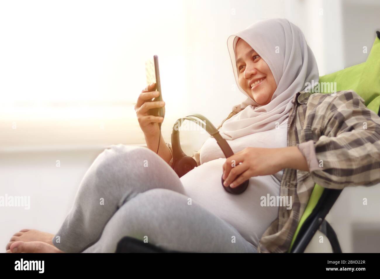 Bella musulmana asiatica incinta mette le cuffie sul suo pancino e apre la  recitazione di Quran o musica classica per il suo bambino ascolto. Felice e  rilassante Foto stock - Alamy