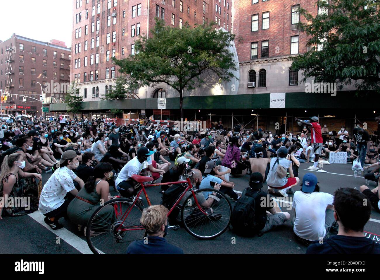 New York City, New York, Stati Uniti. 6 Giugno 2020. I manifestanti che marciano in risposta alla morte di George Floyd afroamericano, mentre si trovano nella custodia della polizia di Minneapolis, e a sostegno del movimento Black Lives Matter, si siedono sul marciapiede all'angolo tra 9th Avenue e West 23rd Street nel quartiere Chelsea di Manhattan oggi. È stata una delle centinaia di proteste negli Stati Uniti e nel mondo in risposta alla morte di Floyd la scorsa settimana. Credit: Adam Stoltman/Alamy Live News Foto Stock