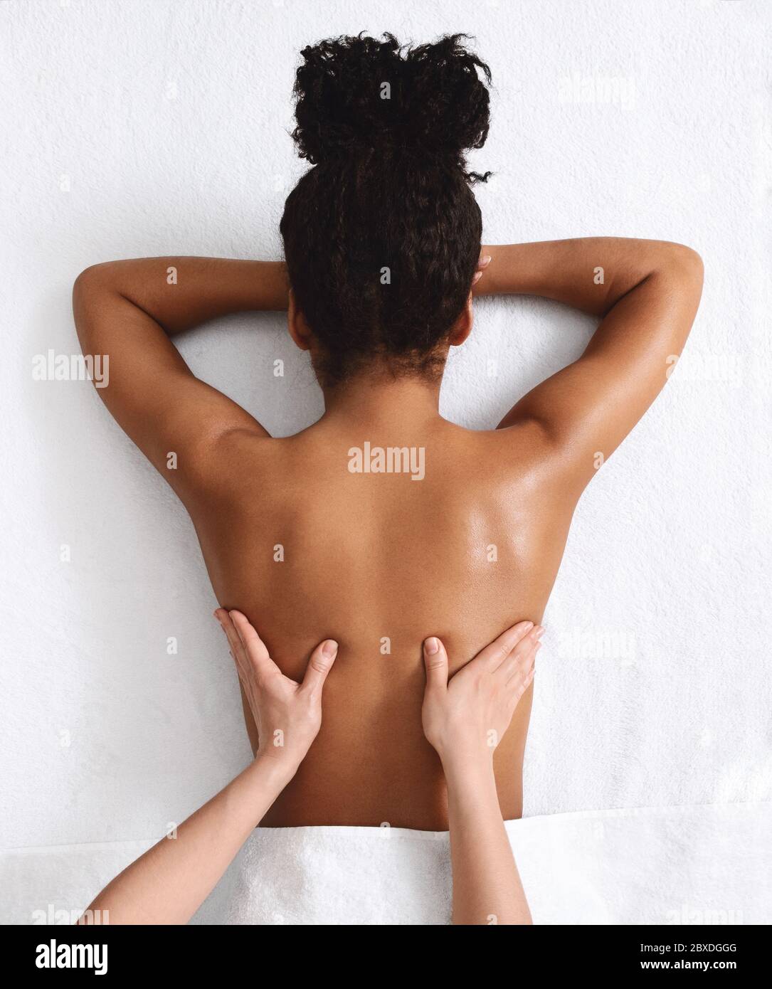 Donna africana irriconoscibile che ha massaggio alla schiena, sfondo bianco Foto Stock