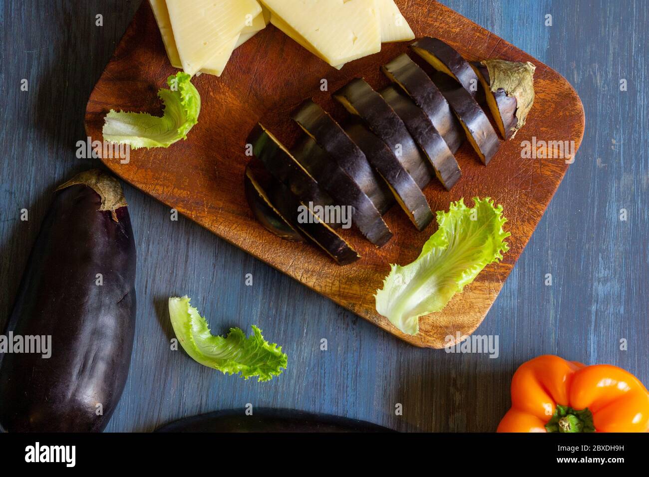 melanzane con formaggio e peperoncini in un motivo su sfondo blu e artistico Foto Stock