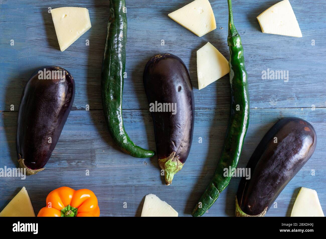 melanzane con formaggio e peperoncini in un motivo su sfondo blu e artistico Foto Stock