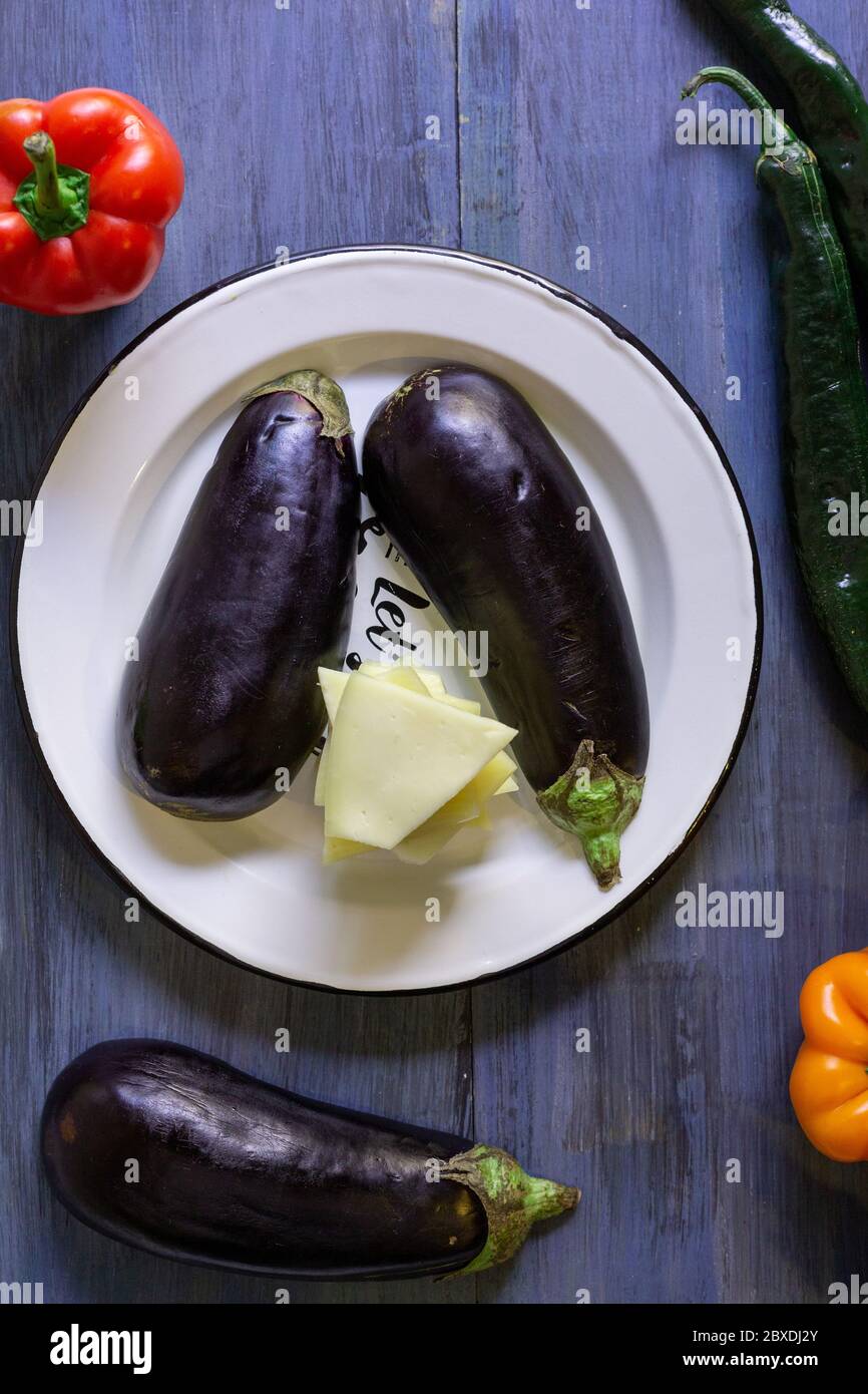 melanzane con formaggio e peperoncini in un motivo su sfondo blu e artistico Foto Stock