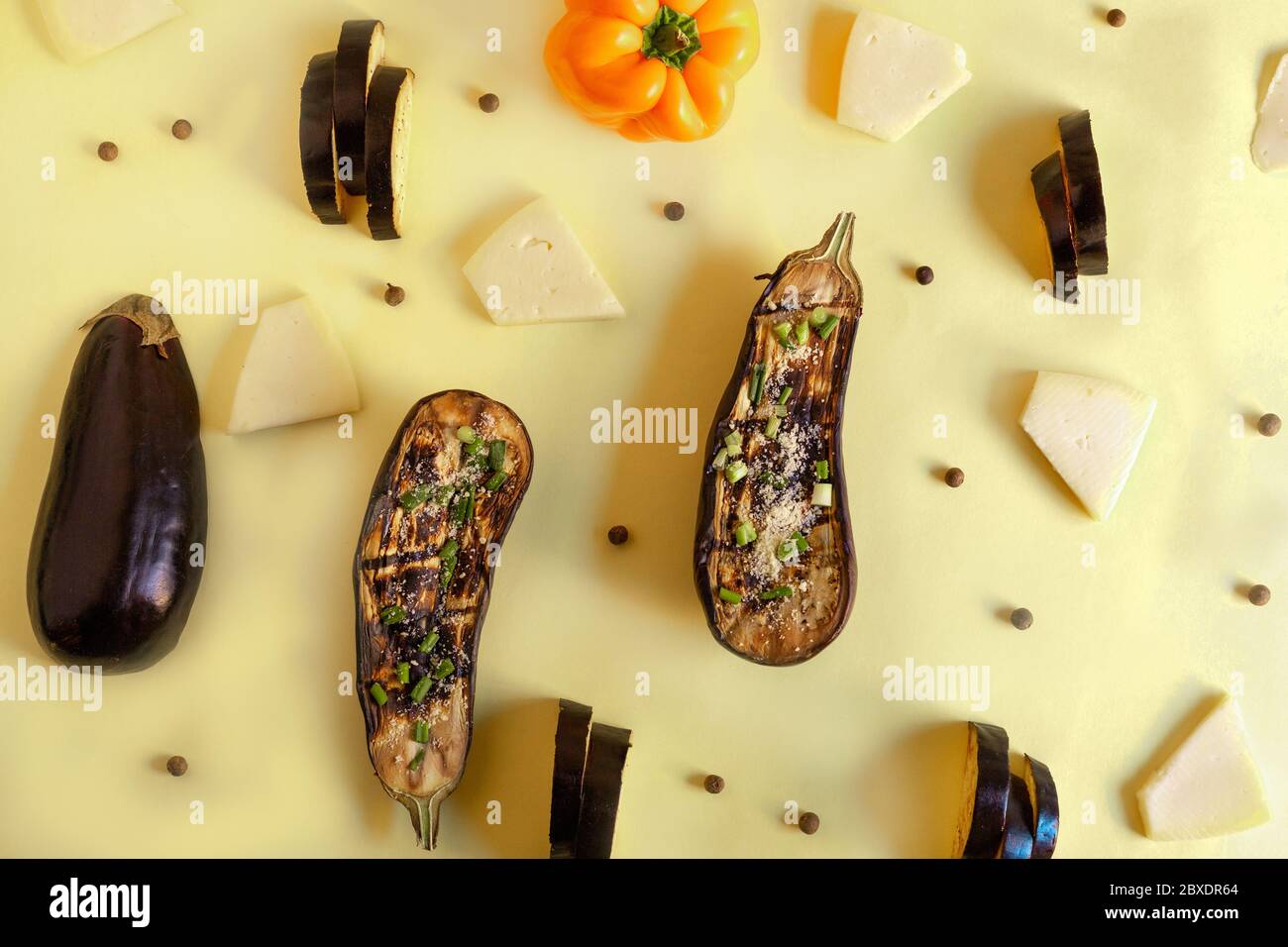 melanzane con formaggio e peperoncini in un motivo su sfondo artistico giallo in legno Foto Stock