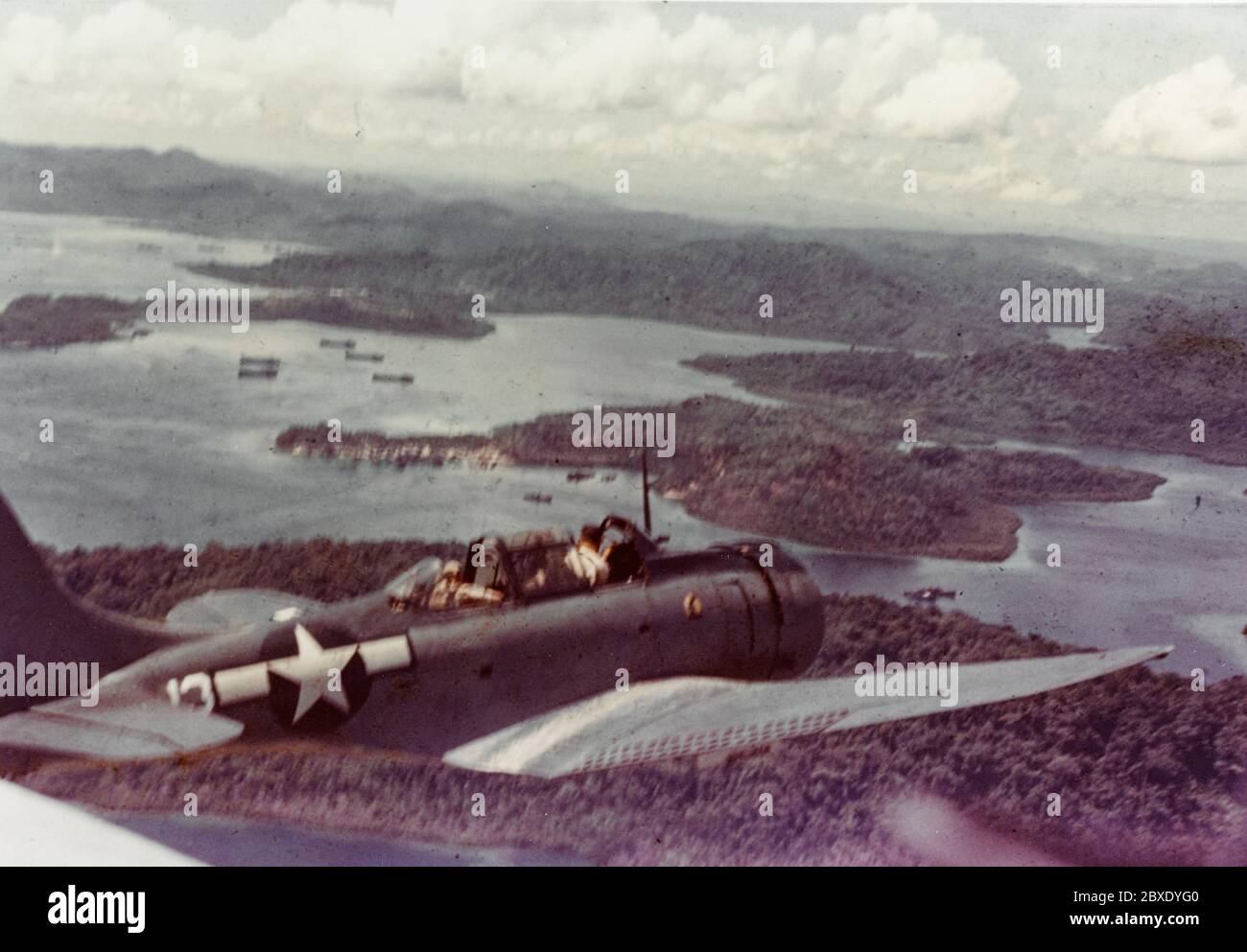 Douglas SBD Aircraft sopra Segi Point, circa 1943-1944. Segi Point, Nuova Georgia, Isole Salomone. Douglas SBD Aircraft sopra Segi Point, circa 1943-1944. Nota gli LSTs nel porto sottostante. Foto Stock