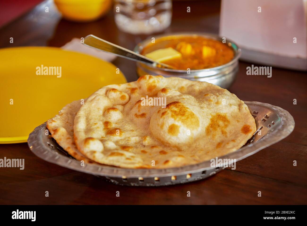Cappati in stile indiano in un piatto sul tavolo con una ciotola di curry. Foto Stock