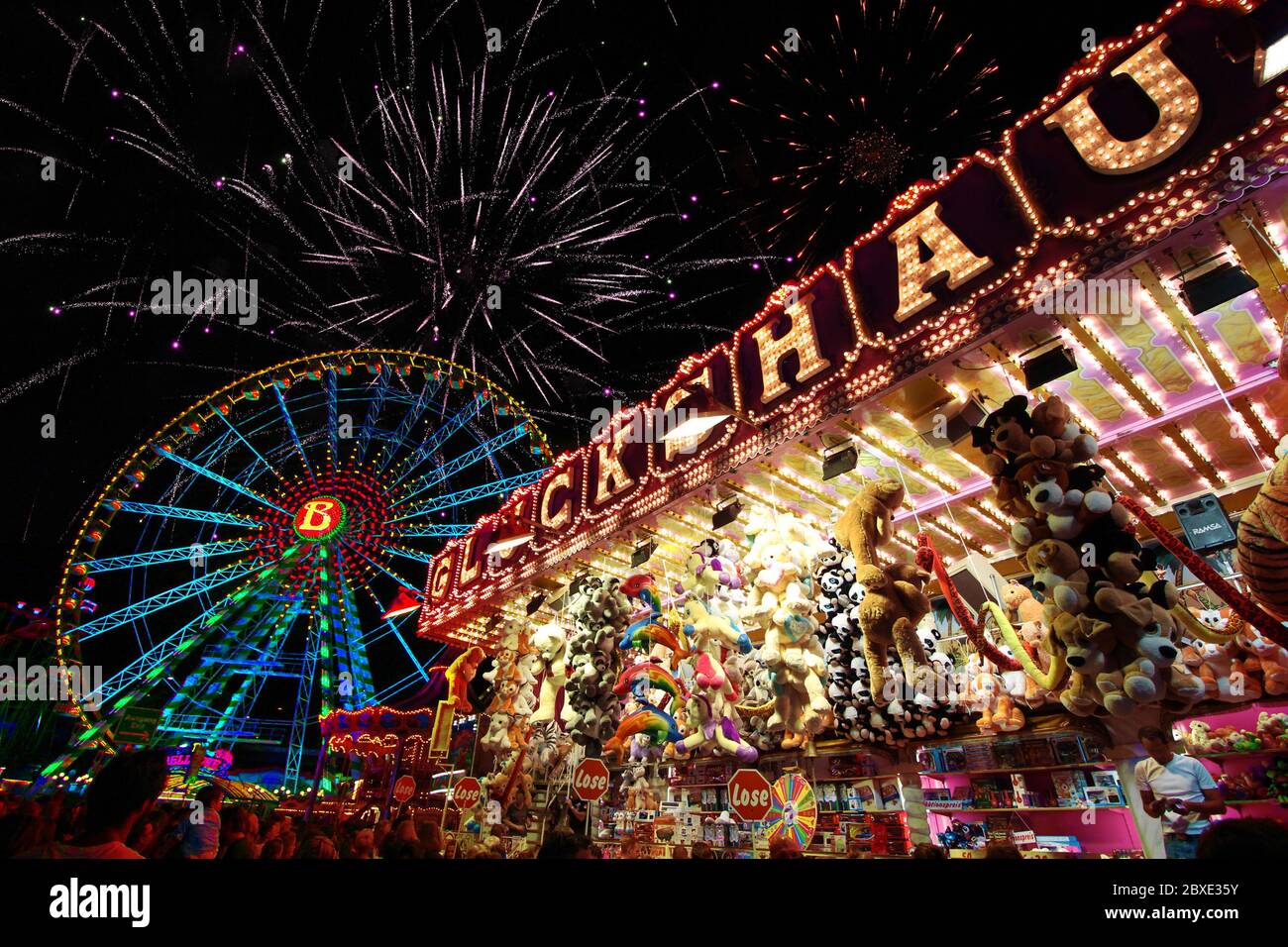 Estate divertente stand gioco equo con una ruota ferris colorata e fuochi d'artificio sullo sfondo. Foto Stock