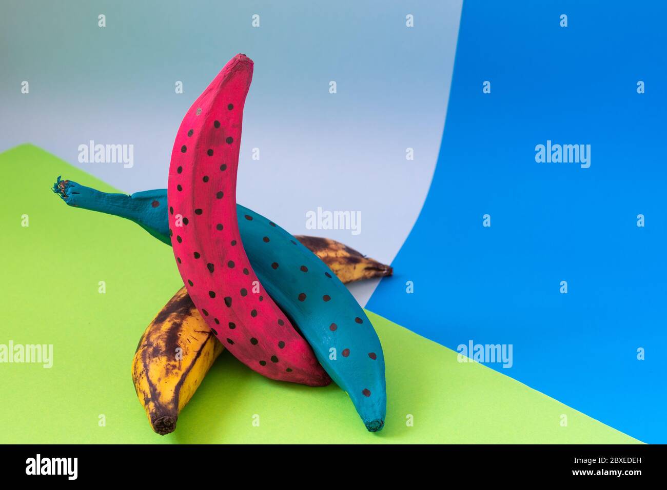 banane colorate su cartone arancione blu Foto Stock