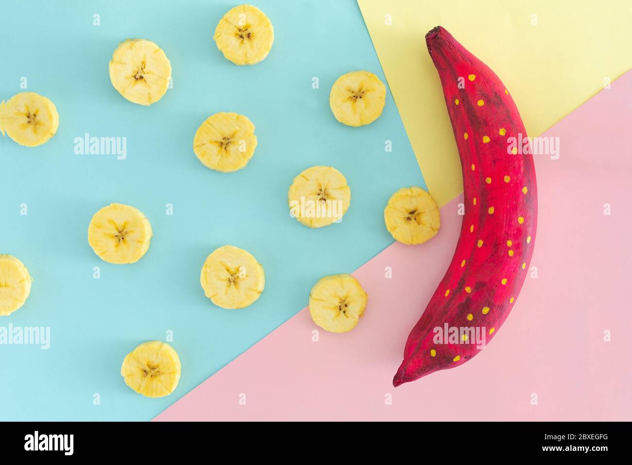 buccia di banana blu con pezzi di banana su sfondo piatto rosa Foto Stock